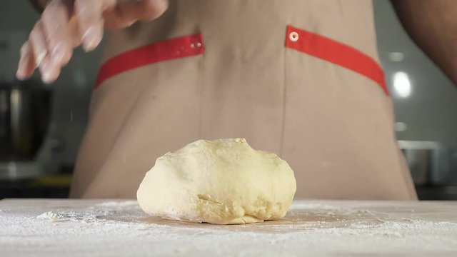 Chef baker throws the dough on the table, slow motion.