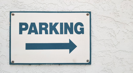 Parking sign on an exterior wall with direction arrow