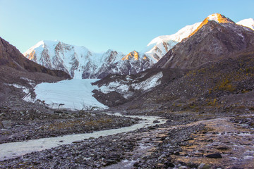 Fototapeta premium The river flowing from the glacier near the snow-white mountains