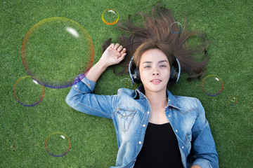 Relaxing women listening music lying down on the grass with headphone , Face
