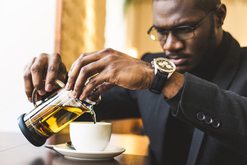 Young handsome dark-skinned businessman in a cafe with a cup of tea.
