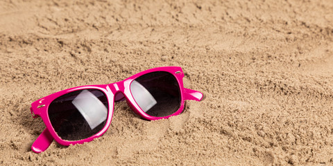 Fototapeta na wymiar sunglasses in sand at a beach