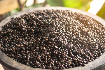 Dark roasted coffee beans In a bamboo weave basket.