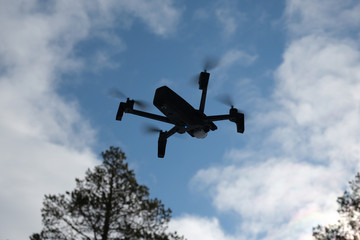Quadcopter on the background of forest and clouds. In the background are forest, clouds and trees.