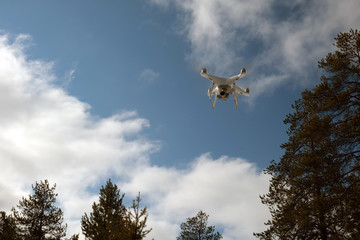 Quadcopter on the background of forest and clouds. In the background are forest, clouds and trees.