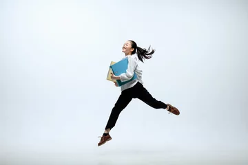 Tuinposter Getting faster and stronger. Happy woman working at office, jumping and dancing in casual clothes or suit isolated on white studio background. Business, start-up, working open-space concept. © master1305