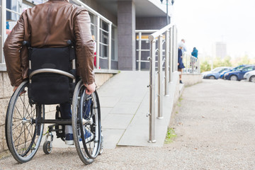 Man in a wheelchair use a wheelchair ramp.