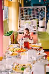 Baby girl in pink in highchair in front of big fest table at birthday party