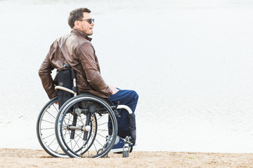 Young man sitting in a wheelchair by the lake.
