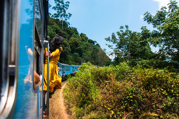 Woman enjoying train ride through Sri Lanka tea plantations - obrazy, fototapety, plakaty