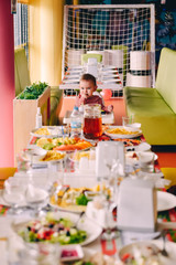 Baby girl in pink in highchair in front of big fest table at birthday party
