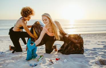 Women cleaning up a sandy beach - Powered by Adobe