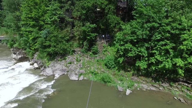 Young man on a zip line over the mountain river in Carpathians