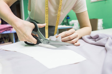 Obraz na płótnie Canvas Sewing workshop. Seamstress at work. Marking and cutting fabric.