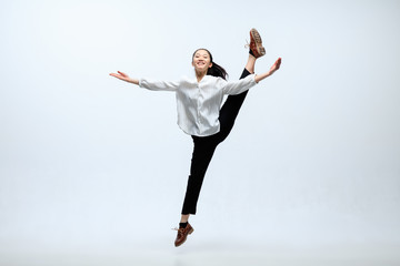 Obraz premium Winged flying by inspiration. Woman working at office, jumping and dancing in casual clothes or suit isolated on white studio background. Business, start-up, working open-space concept.