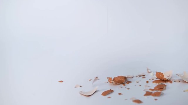 C&aacute;scara de huevo rota cayendo sobre fondo blanco