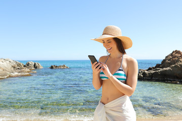 Happy tourist browsing smart phone on the beach