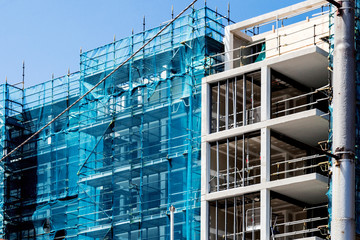 Blue scaffolding fabric lining building exterior.