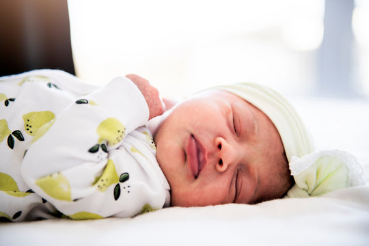 A newborn baby laying down sleeping on a soft white background. Use the photo to represent life, parenting or childhood.