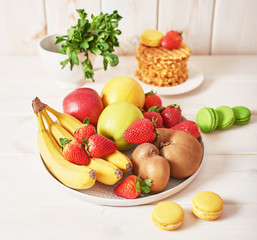 fruit plate (apples, strawberries, bananas, kiwi) on a white wooden background