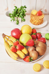 Naklejka na ściany i meble fruit plate (apples, strawberries, bananas, kiwi) on a white wooden background