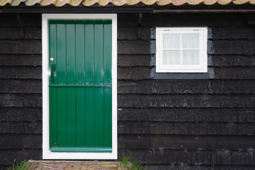 Fototapeta na wymiar Front door of small rural cottage house with wooden wall and green door
