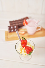 Strawberry cake and chocolate bars on a white wooden background.