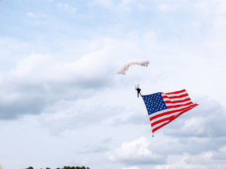 presentation of colors by skydiver carrying huge american flag at sporting event in the united states of amaerica