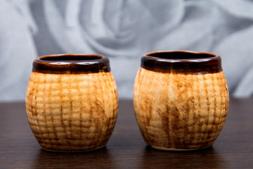old jug on brown background. brown porcelain tea cups. Ceramic cans. small jars. Brown clay dishes. clay pots made of clay material. Two cups of hot coffee on a vintage wooden table