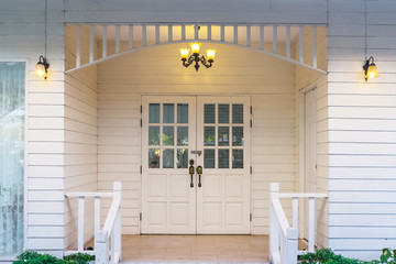 Typical front of vintage small white wooden house with vintage lamp