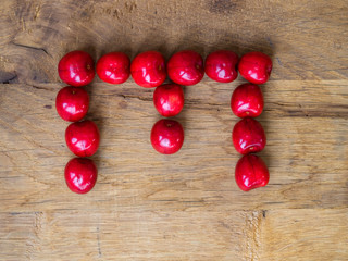 cherry on wooden background as a letter
