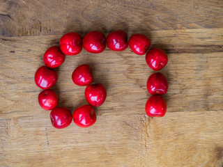 cherry on wooden background as a letter