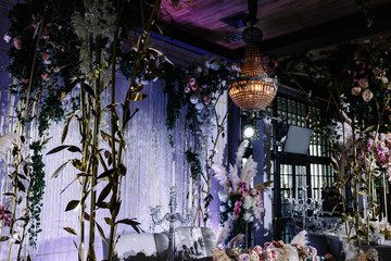 a wedding hall decorated with flowers and a chic chandelier hanging from the ceiling