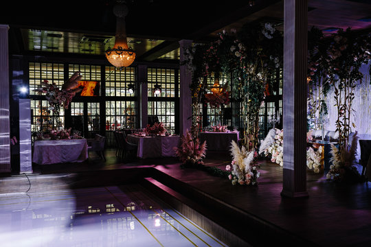 a wedding hall decorated with flowers and a chic chandelier hanging from the ceiling