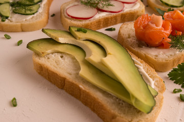 Sandwiches with salmon, cucumber, tomatoes, avocados and greens, vegetable sliced