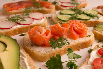 Fototapeta na wymiar Sandwiches with salmon, cucumber, tomatoes, avocados and greens, vegetable sliced