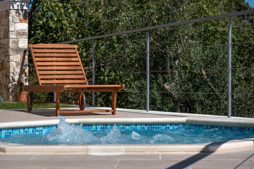 Wooden deck chair near jacuzzi pool in olive yard near luxury apartments on island Brac in Croatia