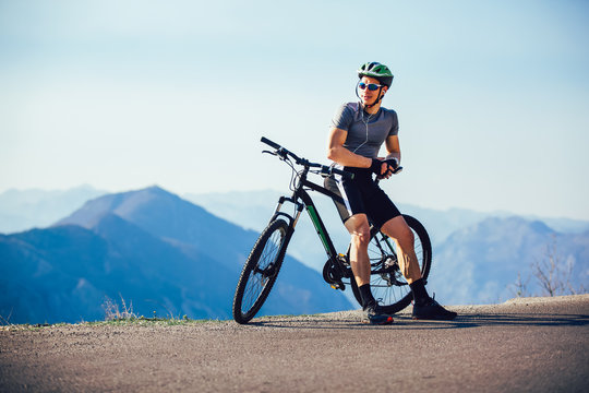 Athletic sportsman cyclist standing with bike enjoying beautiful view.
