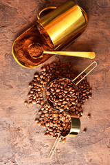 Coffee beans, golden cup of coffee on a brown background.