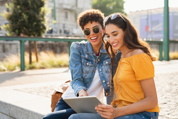 Two women using digital tablet outdoor