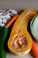 Arrangement of raw food ingredients on the table: butternut squash, cabbage, zucchini, carrot and champignon mushroom. Selective focus.