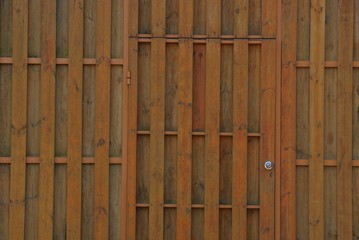 brown wooden background of thin long boards in the wall of the fence