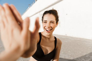 Cheerful young fitness woman giving high five