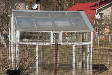 white glass greenhouse in the garden outside the fence
