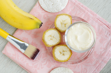 Homemade banana face mask (cream) in the small glass jar and cosmetic brush. DIY beauty treatments...