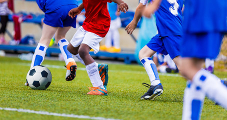Naklejka premium Young Boys in Blue and Red Soccer Jersey Shirts and Soccer Cleats Kicking Soccer Ball. Football Tournament for Youth Soccer Clubs Academies. School Soccer Competition