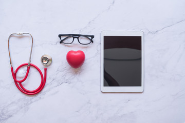 flat lay of good healthy concept,  red heart and stethoscope and tablet on white marble background