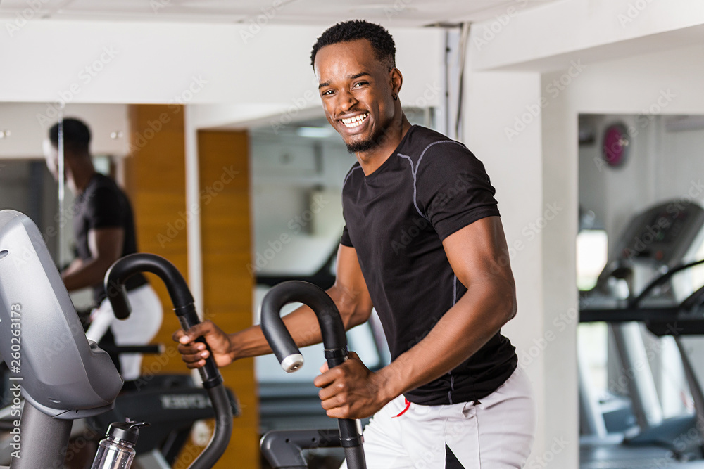 Wall mural black african american young man doing cardio workout at the gym