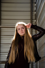 Portrait of a beautiful girl in a dark red dress knee-deep and in a dark leather jacket in the street in the afternoon