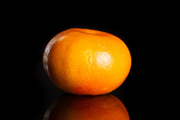 One whole fresh orange mandarine isolated on black glass